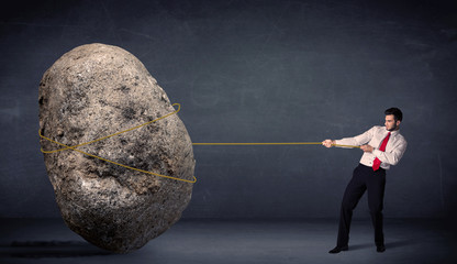 Businessman pulling huge rock with a rope