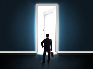 Obraz premium Business man looking at big bright opened door