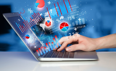 Hand typing on modern laptop notebook computer with graph icons