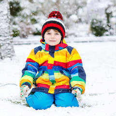 Fototapeta na wymiar Funny preschool boy in colorful clothes happy about snow, outdoo