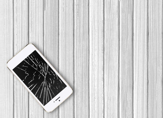Modern broken mobile phone on white wooden background