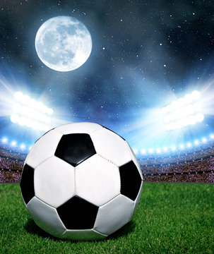 Soccer ball in grass, soccer stadium with the dright lights