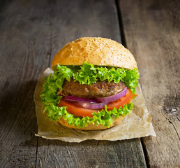 Burger with beef cutlet, lettuce, onions and tomato