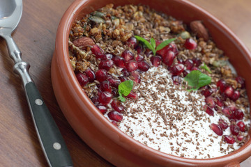 Bowl of granola with pomegranate seeds and yogurt.