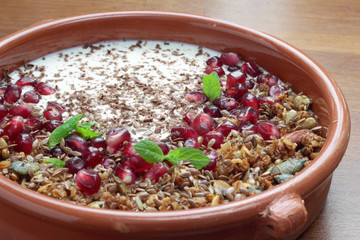 Bowl of granola with pomegranate seeds and yogurt.