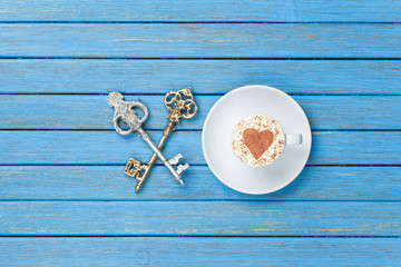 Fototapeta na wymiar Cup of Cappuccino with heart shape symbol and two keys
