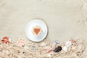 Cup and net with shells on sand