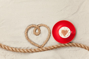 Fototapeta na wymiar Cup of coffee near heart shape rope