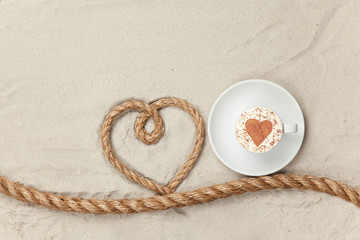 Fototapeta na wymiar Cup of coffee near heart shape rope