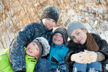 Fototapeta na wymiar Happy children in winterwear laughing while playing in snowdrift