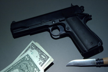 Desk of a criminal: Handgun, knife, and Dollars