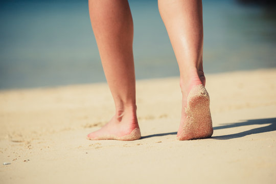 Feet of a young woman walking on the beach