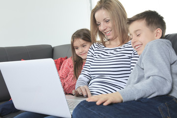 Fototapeta premium Image of friendly family sitting on the sofa and looking at lapt