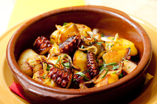 Octopus with fried potatoes in a clay plate