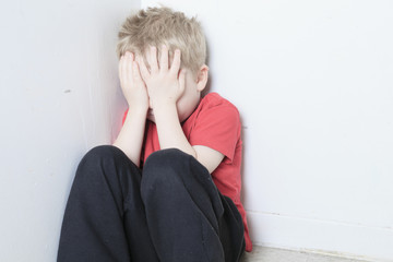 Neglected lonely child leaning at the wall