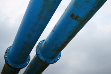 Two parallel blue pipes against a grey sky