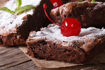 chocolate brownie cake with cherry closeup on paper. Horizontal