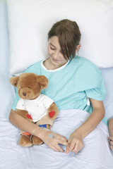 Little girl in hospital bed with teddy bear