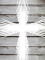 white cross with light rays and old wooden grey background