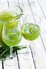 Green estragon lemonade pitcher with glasses on a wooden table