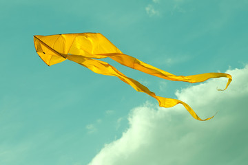Yellow kite flying in the cloudy sky. Toned photo © besjunior