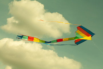 Multicolor kite flying in the cloudy sky. (Toned photo.) © besjunior