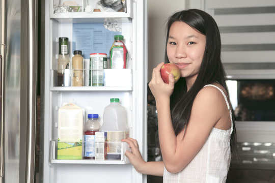Portrait of smiling teenager girl with apple in kitchen