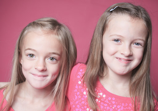 young sister girl poses for a picture isolated on pink