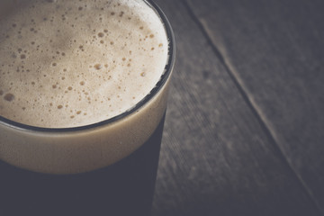 Pint of Dark Beer on Wood Background with Vintage Film Style