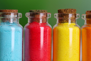 Bottles with colorful dry pigments on bright background