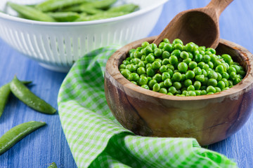 Wooden bowl with fresh sweet petite peas and scoop