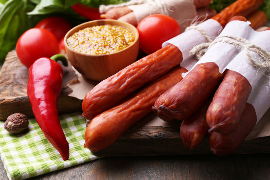 Assortment of thin sausages, mustard in bowl and spices