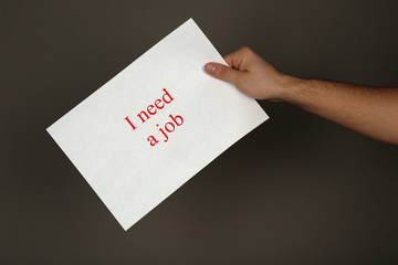 Sheet of paper with inscription I need a job in male hand