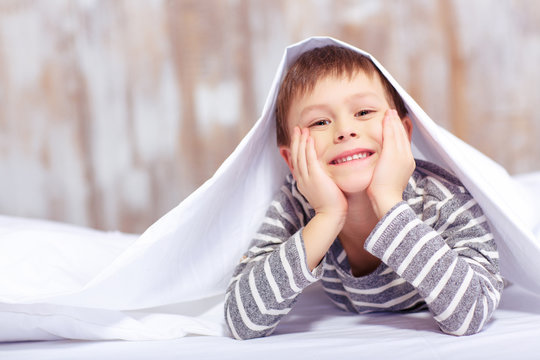 Portrait of a cute little boy under the blanket