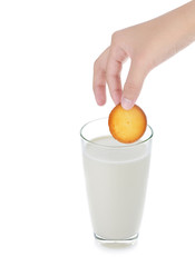 hand holding cookie into glass of milk on white background