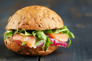 Sandwich with salmon on color wooden background
