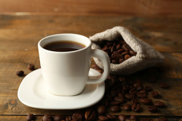 Cup of coffee with beans on rustic wooden background
