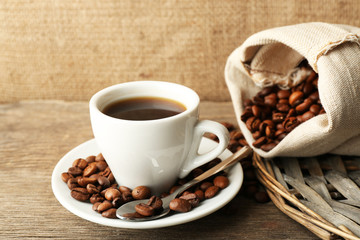 Cup of coffee with beans on rustic wooden background