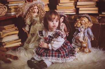 Little beautiful girl among favorite dolls and toys