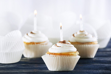 Delicious birthday cupcakes on table on light background
