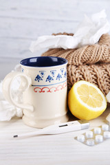 Hot tea for colds, pills and handkerchiefs on table close-up
