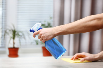 Male hands with sprayer and rag wash windowsill