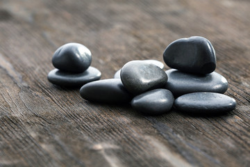 Stack of black sea pebbles on rustic wooden background