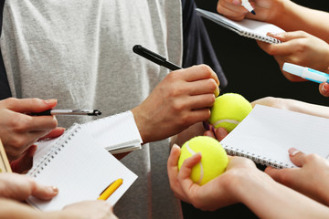 Sportsman signing autograph on tennis ball on dark background - obrazy, fototapety, plakaty