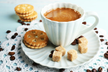 Cup of coffee and tasty cookie on color wooden background