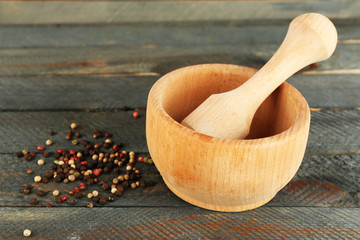 Mixture of peppers in mortar on wooden background