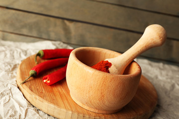 Ground red pepper in mortar with chili pepper
