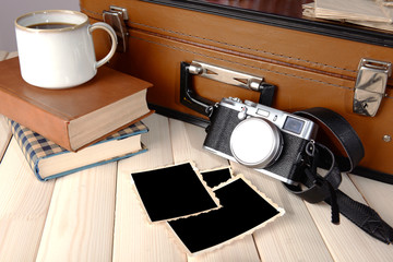 Vintage suitcase with books and camera on wooden background