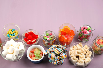 Sweetness in different containers on wooden background