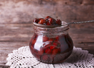 Jar of cherry jam on wooden background